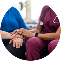 Nurse comforting elderly patient, hands clasped together.