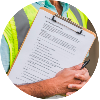 Worker holding clipboard with checklist in safety vest.