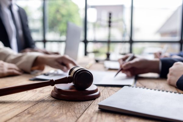 Richterhammer und Hände auf Tisch bei Besprechung