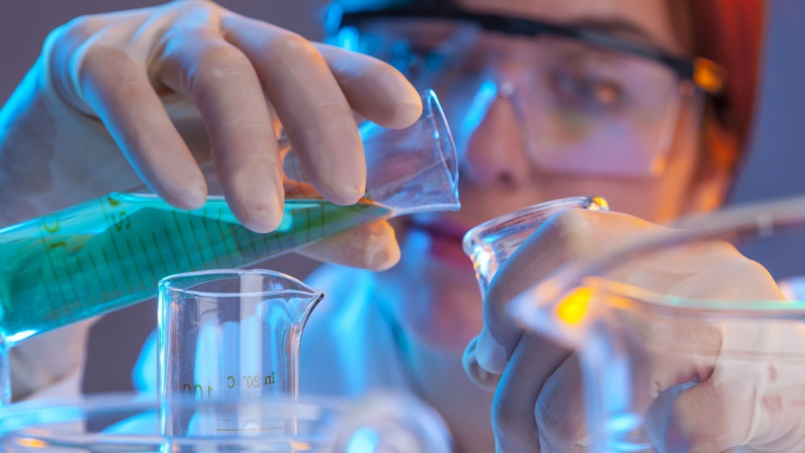Scientist pouring liquid into beaker in laboratory.