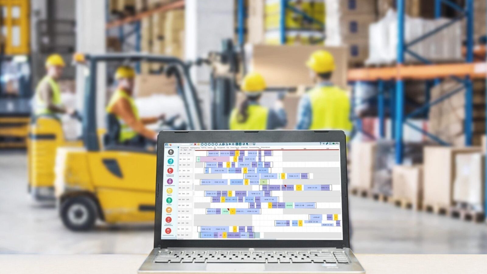 Warehouse management software on laptop in busy warehouse.