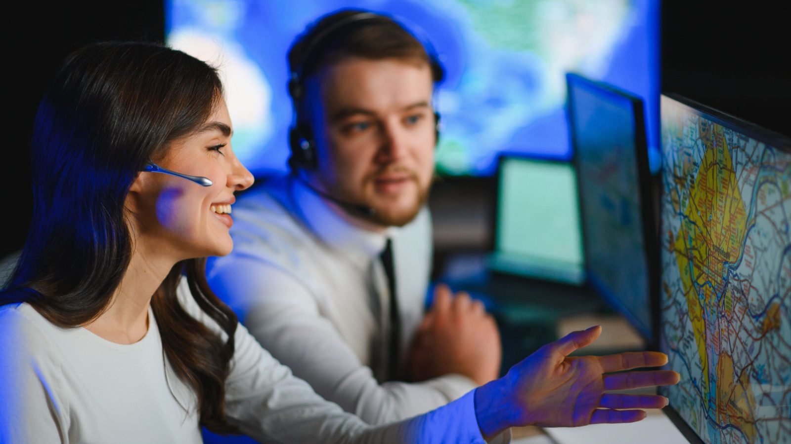 Two operators discussing map on computer screens.