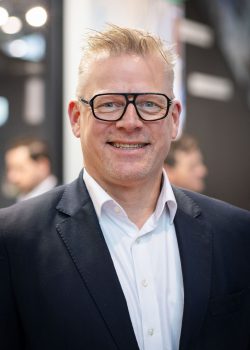 Lächelnder Mann mit Brille auf Messe